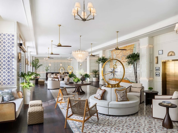 A spacious lobby with a round coffee table, seating areas, and a large wall clock.