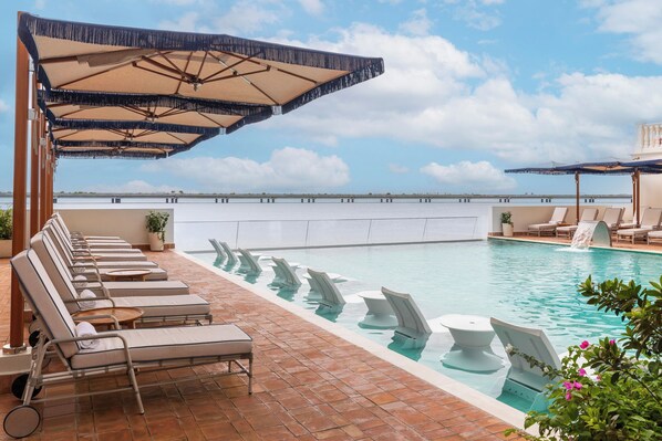 Una piscina al aire libre, sillones reclinables de piscina
