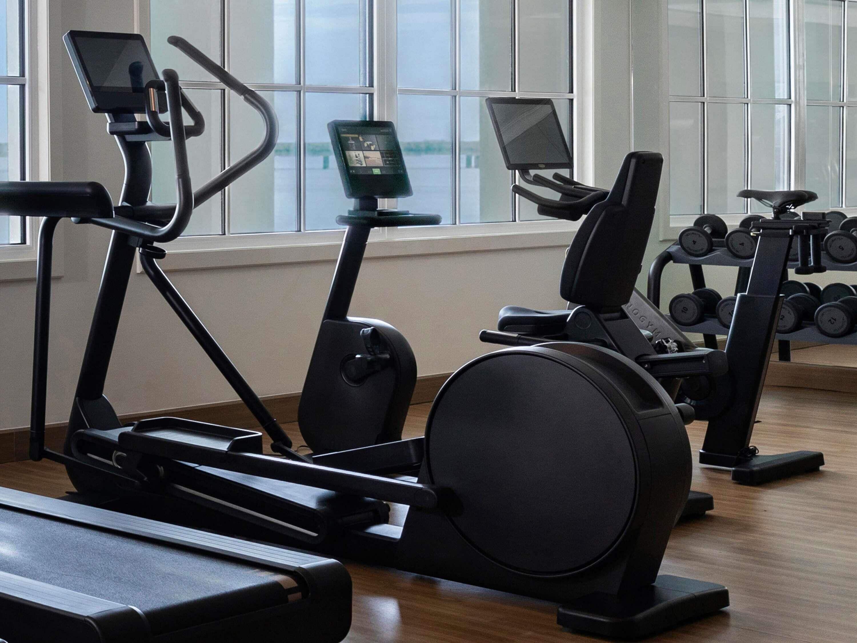 A gym with cardio machines, weight benches, and dumbbells.