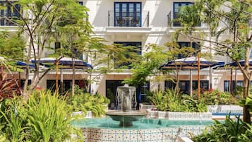 A courtyard with a fountain, surrounded by lush greenery and a tiled pool.