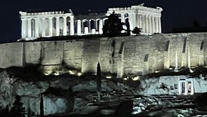 A classical building with columns, illuminated at night, situated on a rocky outcrop. - Park Minimal (Marousi)