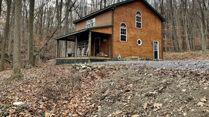 Eine Holzhütte mit Veranda, umgeben von einem Wald.