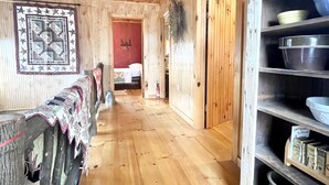Ein Holzinnenraum mit einer langen Diele, einer roten Tür und Regalen mit Küchenutensilien.
