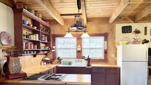 Eine Küche mit Holzausstattung, einem weißen Kühlschrank, einer Spüle und einer Kochinsel aus Holz.