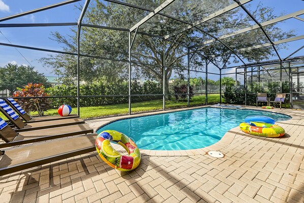 An indoor pool with clear glass walls, lounge chairs, and inflatable rings. - Windsor Hills Private Pool Home ~~ 3 Miles to Disney World w/Tasteful Theming!! (Kissimmee)