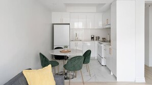 A modern kitchen with white cabinets, a dining table with chairs, and a refrigerator. - Modern 1 BR 1BA in center of Old Mtl | St Paul St (Montréal)