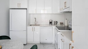 A modern kitchen with white cabinetry, a built-in dishwasher, and a coffee maker. - Modern 1 BR 1BA in center of Old Mtl | St Paul St (Montréal)
