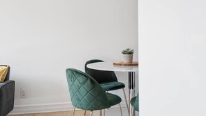 A dining area with a round table, two green upholstered chairs, and a small potted plant on the table. - Modern 1 BR 1BA in center of Old Mtl | St Paul St (Montr éal)