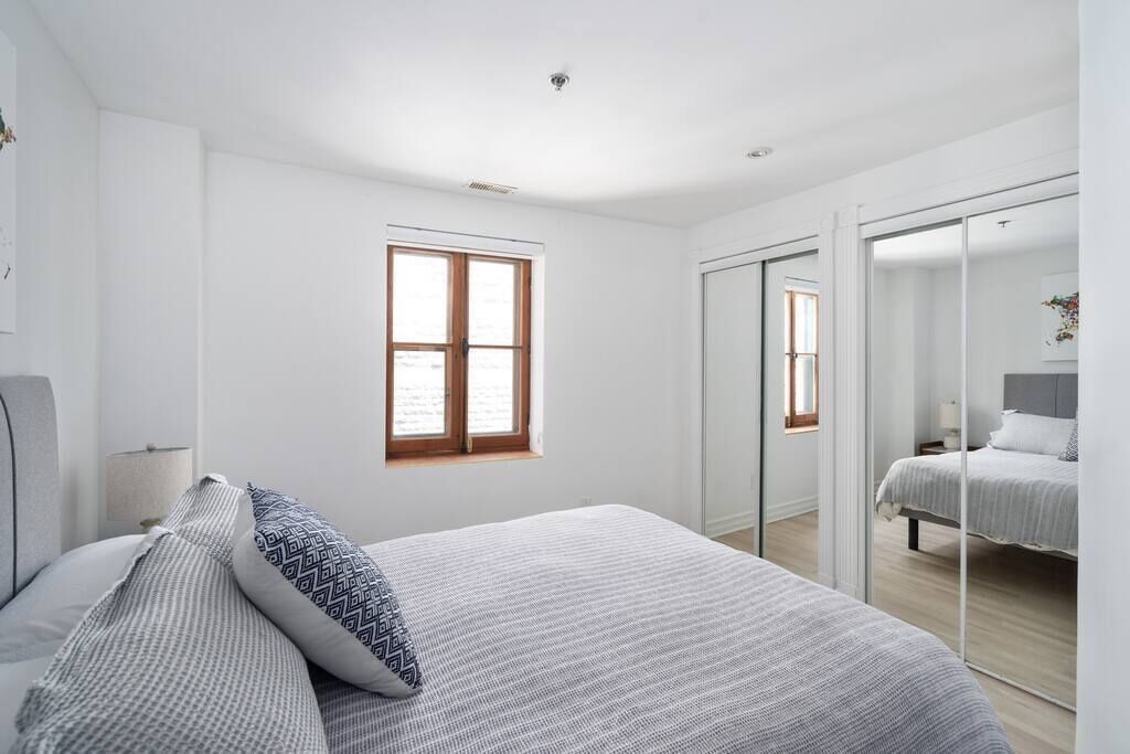 Un dormitorio moderno con una cama grande, una ventana y una puerta corredera que da a otra habitación.