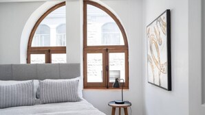 A bedroom with a large bed, two windows, a bedside table with a lamp, and a framed artwork on the wall. - Sublime 3BR 2BA Apt | Old Mtl | St Paul ST | (Montréal)