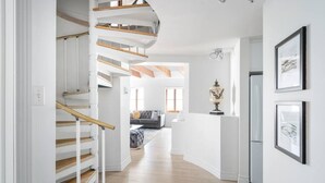 A modern interior with a spiral staircase, a living area with a sofa and a coffee table, and framed artwork on the walls. - Sublime 3BR 2BA Apt | Old Mtl | St Paul ST | (Montréal)