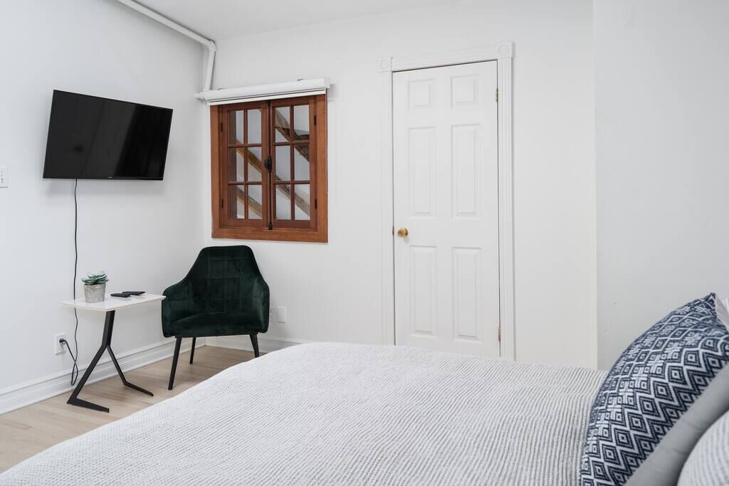 Une chambre à coucher avec un lit, un bureau, une chaise, un téléviseur et une porte.