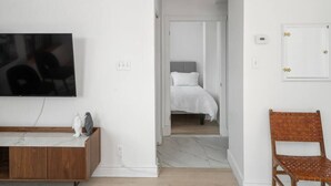 A modern bedroom with a bed, a television, and a wooden bench. - Chic & Modern 3B 1B Apt | Old Mtl | St Paul St | (Montréal)