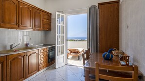 Una cocina con armarios de madera, un lavabo y una zona de comedor con una mesa y sillas.