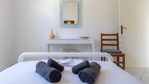 Una habitación de hotel con una cama, un escritorio, una silla y un espejo en la pared.