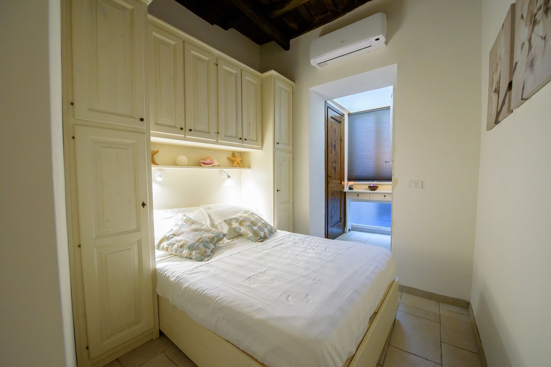 Une chambre à coucher avec un lit, une armoire blanche et un puits de lumière.