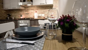 A dining table set with a bowl, wine glasses, and a vase with flowers. - NEW NAVONA ELEGANT APARTMENT (Roma)