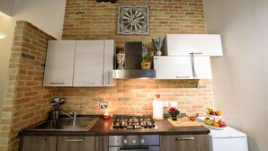 A kitchen with a brick wall, stainless steel appliances, and white cabinets. - NEW NAVONA ELEGANT APARTMENT (Roma)