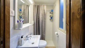 A small bathroom with a white sink, mirror, and toilet. There is a shower curtain and a window. - NEW NAVONA ELEGANT APARTMENT (Roma)