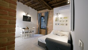 A bedroom with a bed, a desk, and a chair, a TV mounted on the wall, and a window with curtains. - NEW NAVONA ELEGANT APARTMENT (Roma)