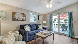 A living room with a blue sofa, a wooden coffee table, and a floor lamp. - Tropical Beach Bungalow Up | 3 bedrooms | Across Street from Beach | Deck (Fernandina Beach)
