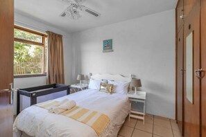 Relax in this inviting room with a large bed, bedside tables, and a charming sailboat painting.