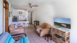 A compact living space with a kitchenette, a sofa, a TV, and a ceiling fan. - Sunny Tides Holiday Inn (Kingsburgh)