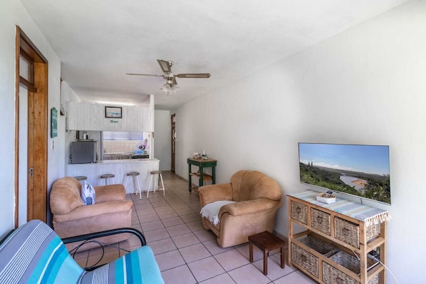 A compact living space with a kitchenette, a sofa, a TV, and a ceiling fan.