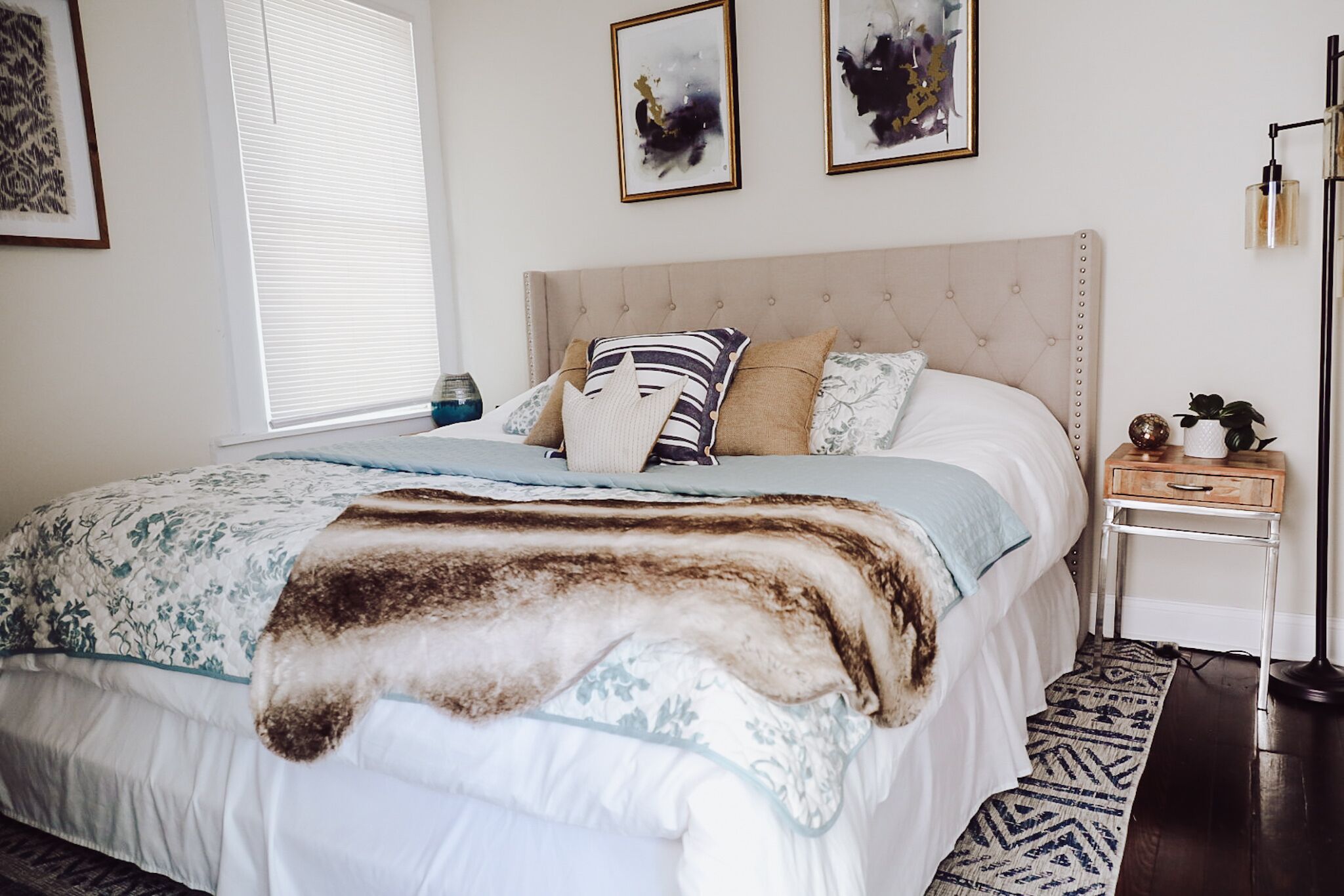 A neatly arranged bedroom with a bed, bedside tables, and artwork on the walls.