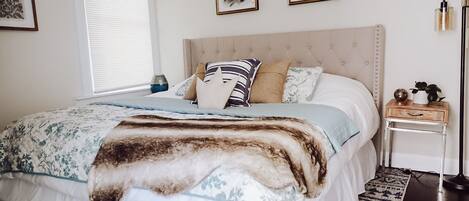 A neatly arranged bedroom with a bed, bedside tables, and artwork on the walls.