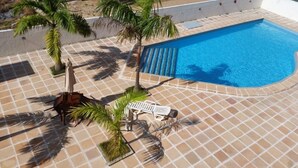 A swimming pool with tiled flooring, palm trees, and lounge chairs. - Calypso solar building A gated community in Atalaia close to the beach. (salinopolis)