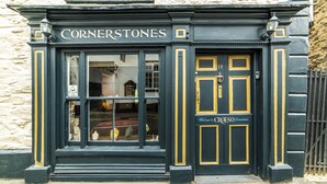 A black storefront with the name "Cornerstones" and a sign reading "Welcome to Cornerstones." - Cornerstones - 16th Century House overlooking River in Llangollen (LLANGOLLEN)