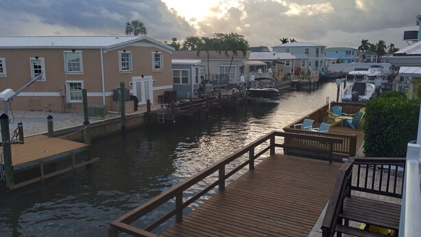A marina with docked boats, a wooden deck, and buildings with a uniform architectural style.