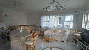 A spacious living room with a dining area, a sofa, a TV, and a glass-top coffee table.