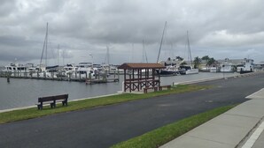 A marina with boats docked, a wooden gazebo, and a bench along the waterfront.