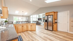 Una cocina amplia con una isla grande, armarios de madera y un refrigerador de acero inoxidable.