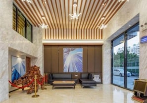 Un vestíbulo con diseño moderno, que presenta un techo de madera, un ventanal grande y una zona de estar con sofá y mesa de centro.