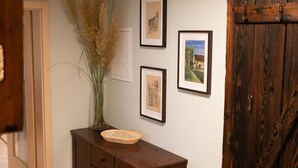 A hallway with a wooden cabinet, a vase with pampas grass, and three framed pictures on the wall.