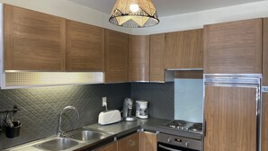 Una cocina moderna con armarios de madera, un lavamanos de acero inoxidable, horno integrado y cafetera.