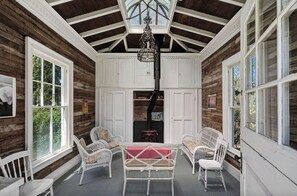 Relax in a charming outdoor space with a wooden ceiling, wicker chairs, and a small table.