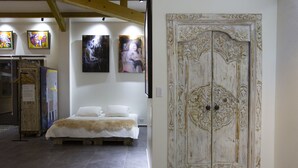 Ein Schlafzimmer mit einem Bett, einer großen, verzierten Tür und Bildern an den Wänden.