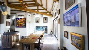 Eine großzügige Galerie mit einem Holztisch und Stühlen, umgeben von verschiedenen Kunstwerken an den Wänden.