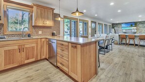 Een moderne keuken met houten kastjes, een groot eiland en een betegelde achterwand.