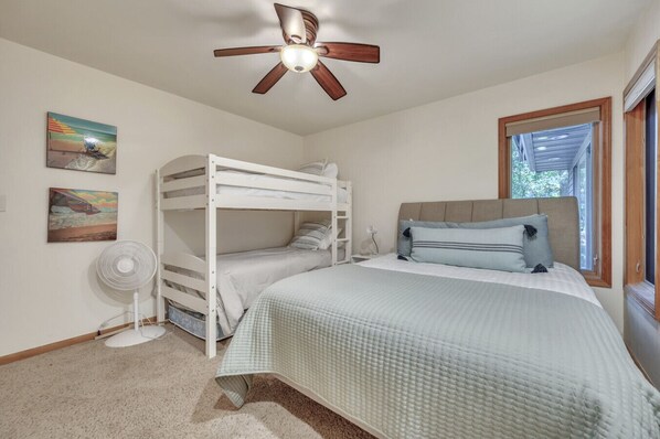 A bedroom with a bunk bed, a single bed, a ceiling fan, and a window with a view of greenery. - Caught on the Canal just steps from West Lake Okoboji off famous Miller`s Bay (Milford)