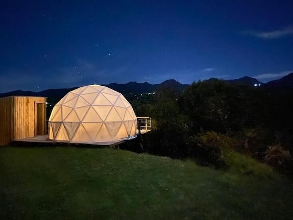 A geodesic dome structure with a wooden exterior and a platform.