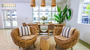 A spacious room with a large window, wicker furniture, and hanging lights. - Casa Ocean (Miami Beach)