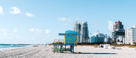 A beach with a lifeguard tower and buildings in the background.