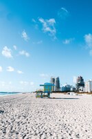 Una playa con una torre de salvavidas y edificios al fondo.