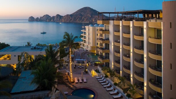 Um hotel com várias varandas, piscina e vista para o mar.