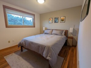 Un dormitorio con cama, ventana, mesita de noche y decoración en la pared.